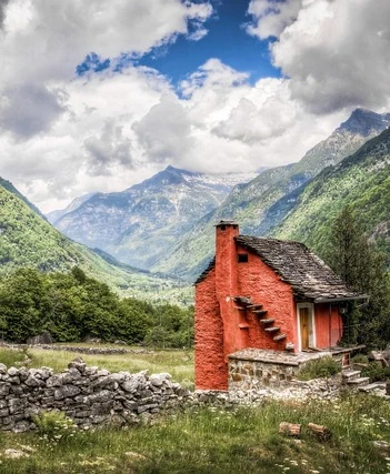 Image of a red cottage nestled in the Swiss alps